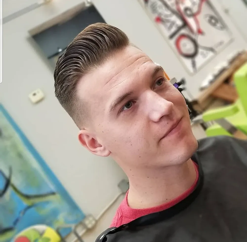 Man with a side-swept pompadour and tapered sides in the chair at Hair Culture America
